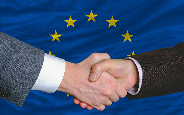 businessmen handshake after good deal in front of europe flag stock photo