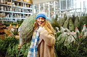 Beautiful young woman buys a Christmas tree at the fair.