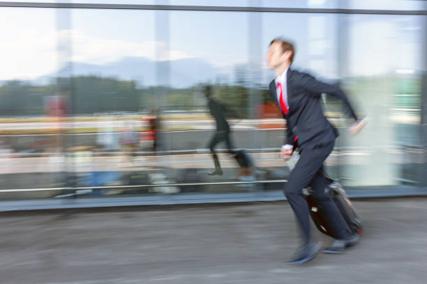 good looking caucasian pilot running towards the airport entrance - cabin crew pilot airport walking imagens e fotografias de stock