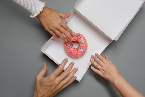 Family with donut. Hands and sweet  dessert closeup, top view