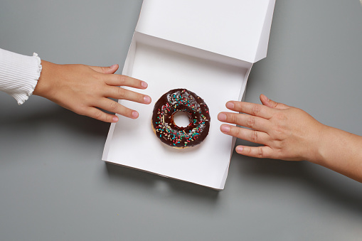 Colorful chocolate donut and hand, top view