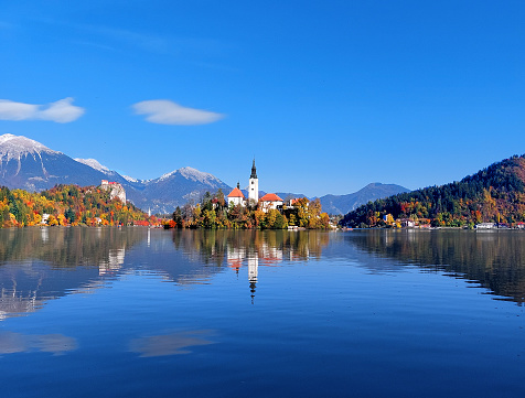 Lake Bled and church in the middle, beautiful mountains in background and crystal clear water.
