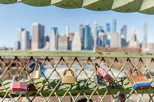 Brooklyn Queens, New York City, USA - February 11, 2023: love padlock hanging on a fence in front of manhattan on a winter day