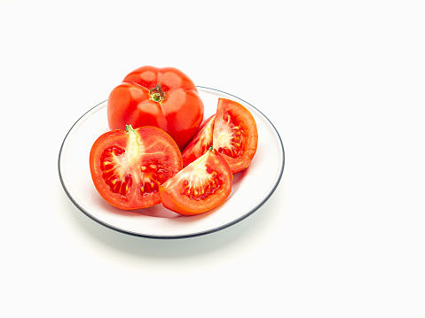 Fresh tomatoes on a white plate on a white background. Top view. Close-up photo. Health foods concept