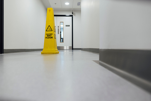 Full length of an empty hospital training facility corridor in Newcastle, England. There is a wet floor cone on the corridor floor.