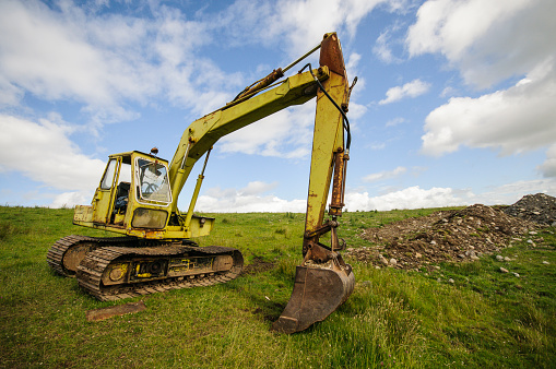 Tracked excavator digger in a rural farm field.