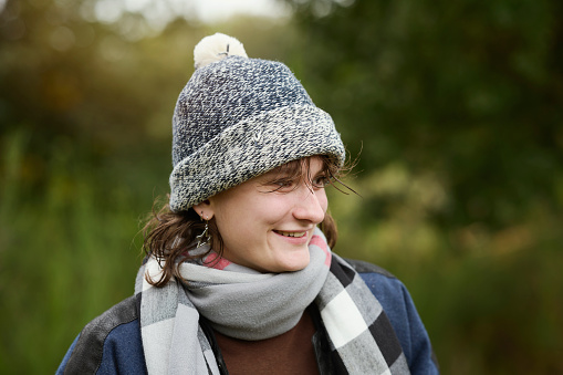 Portrait outdoors of young woman in autumn forest looking away