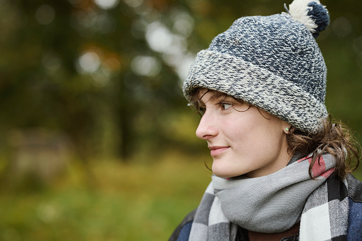 Portrait outdoors of young woman in autumn forest looking away