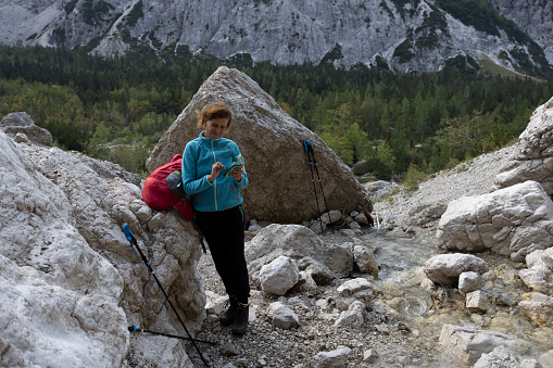 Female Hiker texting a message from her phone in remote location while hiking