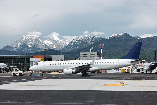 Commercial airplane parked at the airport. Beautiful Alps in the background.