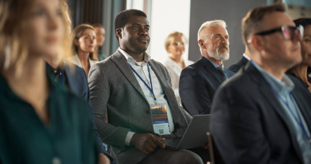 istock Black Man Sitting in a Crowded Audience at a Business Conference. Corporate Delegate Using Laptop Computer While Listening to an Inspirational Entrepreneurship Presentation About Developing Markets. 1757727112