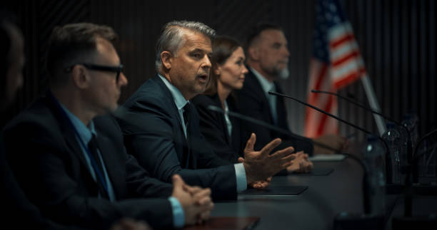 istock Caucasian Male Organization Representative Speaking at Conference in Government Building. Head Of USA Delegation Delivering a Speech at an International Political Summit. Diverse Delegates Listening. 1757729843