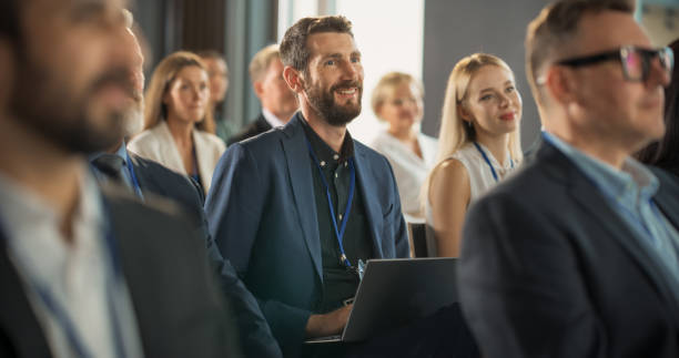 istock Caucasian Man Sitting in a Crowded Audience at an IT Conference. Delegate Using Laptop Computer to Take Notes. Software Developer Watching Presentation About New High Tech Products and Cloud Solutions 1757731471