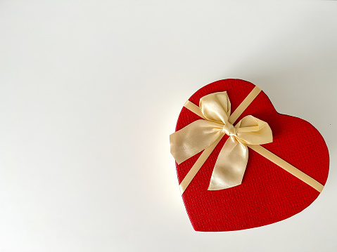 Gift box wrapped in brown paper over white background and a red object in heart shape over white background.Conceptual image for Valentine's day -holiday. Image shoo.t in studio