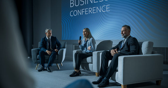 International Business Conference: Host Asking Caucasian Female Tech CEO a Question In Front Of Audience Of Diverse Attendees. Successful Woman Delivering Inspirational Speech For Women In Leadership.