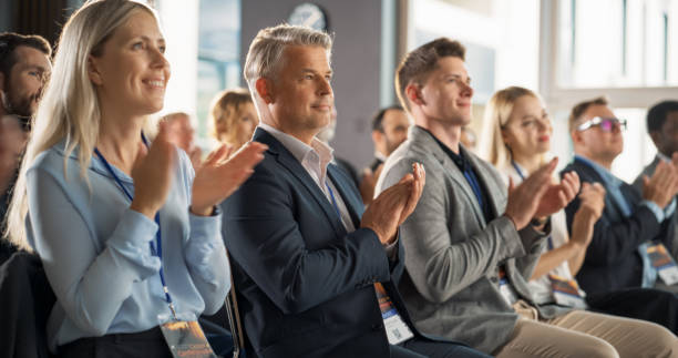 istock Male CEO Sitting in a Bright Crowded Auditorium at a Tech Conference. Confident Man Applauding After a Successful Keynote Presentation. Specialist Inspired by Latest Technological Advances. 1757745737