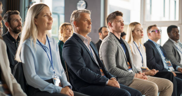 istock Male CEO Sitting in a Bright Crowded Auditorium at a Technology Conference. Confident Man Watching Interesting Keynote Presentation. Specialist Inspired by Latest Technological Advances, Developments. 1757746328