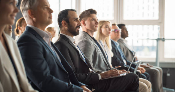 istock Multiethnic Man Sitting in Crowded Auditorium at Conference. Middle Eastern Businessman Listening To Keynote And Typing On Laptop. Specialist Watching Technology Presentation About Software Solutions. 1757749086