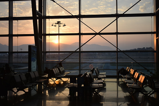 Warm sunrise over distant mountains through the glass facade of an airport departures waiting area. Taken in Izmir, Turkey.