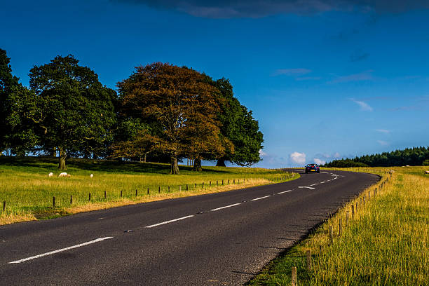 Road countryside Picture of the English countryside in South Yorkshire near Chatsworth house. A road passing by is the main interest in the picture. A convertible BMW can be appreciated in the background. chatsworth house photos stock pictures, royalty-free photos & images