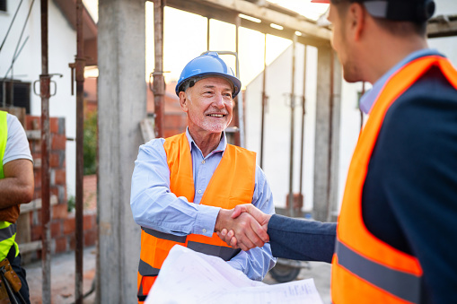 Male Caucasian architect handshake with building contractor or engineer during an meeting on a construction site