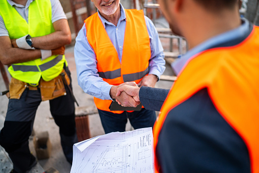 Unrecognizable male Caucasian architect handshake with building contractor or engineer during an meeting on a construction site