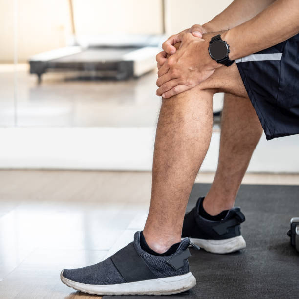 istock Sportive man feeling knee pain or rheumatoid arthritis while sitting on workout bench in fitness gym. Male athlete suffering from acute knee joint inflammation symptom. Sport injury concept 1757791968