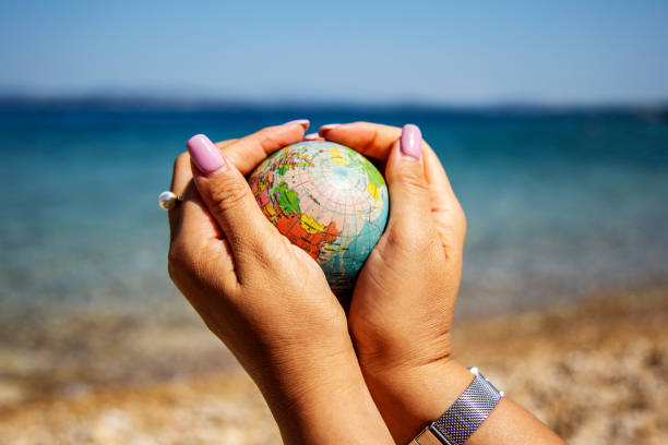 istock Female hands holding a globe earth on the beach. Ecology, warming, social issue, warming climate, no war concept 1757809255