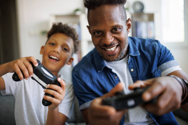 Father and son playing video games at home stock photo