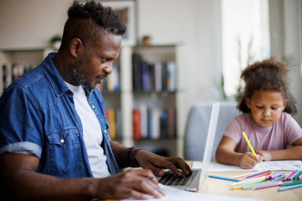 istock Father working on laptop while his daughter drawing beside him at home 1757822642