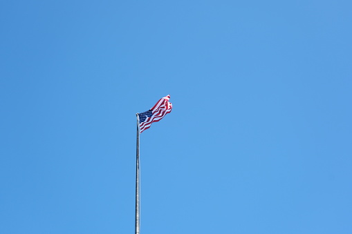 Tattered American Flag, Still Flying Free and Proud.  This image is symbolic of the American spirit, even when tired and rough around the edges, America goes forward.
