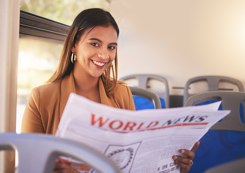 Portrait, bus and woman with a newspaper, smile and travel with world news, happy and student. Face, worker and girl with transportation, info and reading newsletter with happiness and professional