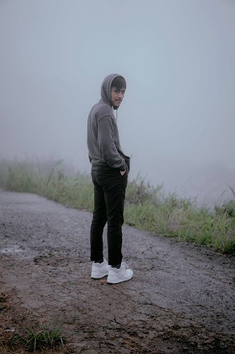 An Asian man looks at the camera with a background full of fog