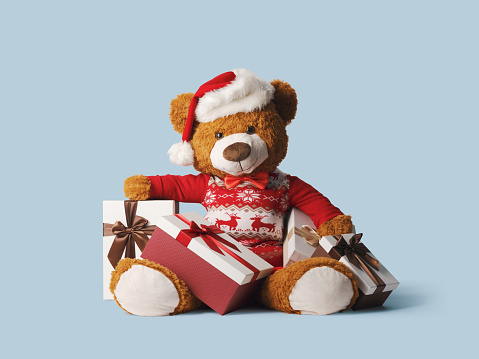 Cute teddy bear wearing a Santa hat and Christmas gifts, holidays and celebrations concept