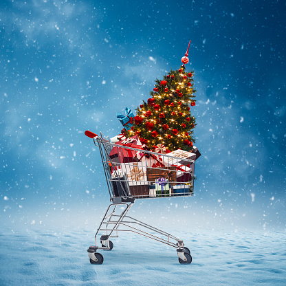 Shopping cart full of gifts and decorations and snow falling, Christmas shopping concept