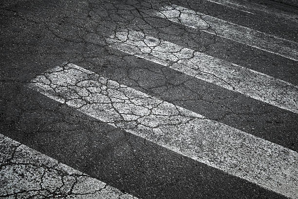 istock Pedestrian crossing marking on old damaged asphalt road 175789836
