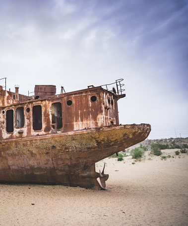 Rusty ships and boats in the desert at the bottom of the dried up Aral Sea in Uzbekistan, an ecosystem tragedy