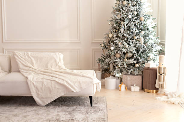 istock Modern interior living room with large light  corner sofa and Xmas tree. Comfortable couch with three cushions and a blanket standing in bright room interior with grey carpet in a modern interior. 1757911350