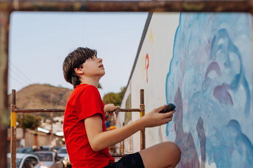 Boy working on a mural in the city