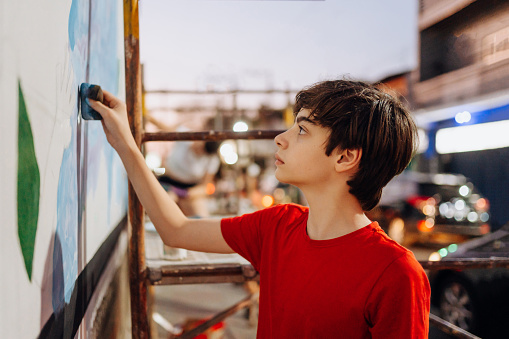 Boy painting graffiti in the city