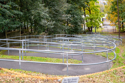 Asphalt sidewalk with steel railings with multiple returns and bends with trees in the background.