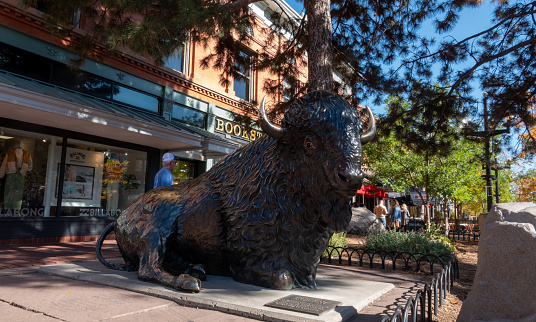 Boulder, Colorado, USA-October 23, 2023: Bison statue, shoppers and browsers walking along the sidewalks of historic Pearl Street Mall in downtown Boulder, Colorado.