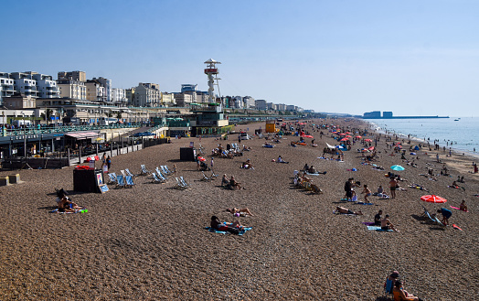 Brighton, UK - September 9 2023: people sunbathe at Brighton Beach on a sunny, warm day.