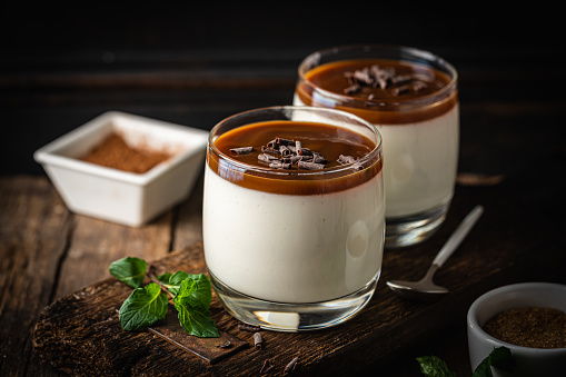 Vanilla panna cotta desert with caramel sause and chocolate in glasses