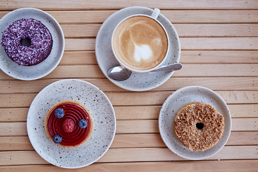 istock Cappuccino and assorted desserts, tart and donuts on the wooden table. Top view food 1757967062