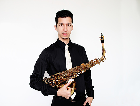 White male saxophonist wearing black long sleeves shirt holding golden saxophone looking forward. Photo with white background.