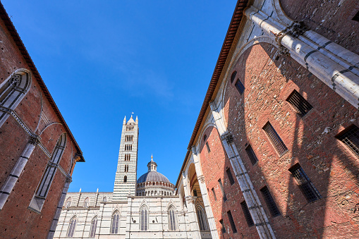 The suggestive and detailed view over the rooftops of Rome from the terrace of the monumental staircase of Trinità dei Monti, better known as Spanish Steps, in the historic and baroque heart of the Eternal City. In the foreground the dome of the Basilica of Santi Ambrogio e Carlo, along Via del Corso, behind the majestic dome of St. Peter's Basilica on the horizon. In 1980 the historic center of Rome was declared a World Heritage Site by Unesco. Image in 16:9 and high definition format.