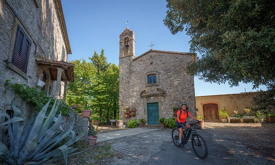 senior woman cycling in a village near Laterina, Province Arezzo in Tuscany, Italy