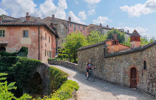 senior woman cycling in a village near Laterina, Province Arezzo in Tuscany, Italy
