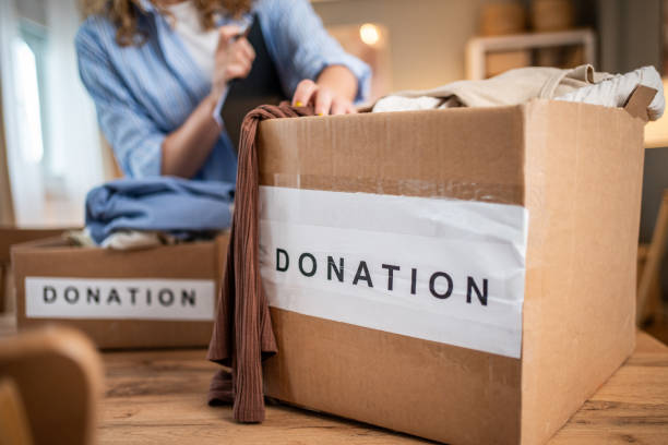 istock A caring young woman packs clothes for donation into a cardboard box 1758010835